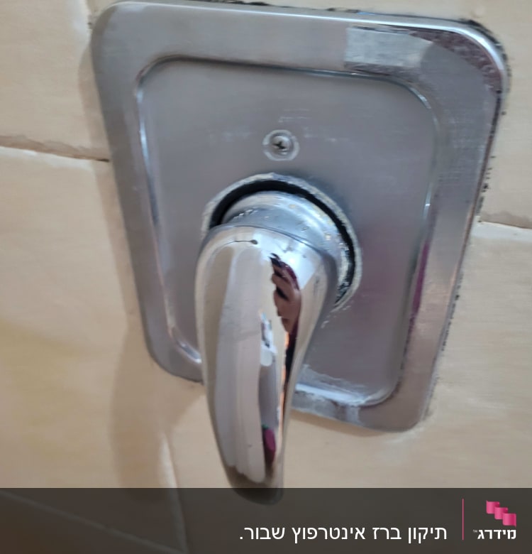 ידית ברז מתכתית על קיר אריחים